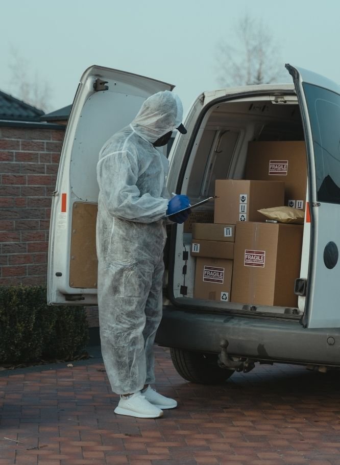 Mover writing notes in a notebook while van is loaded with items